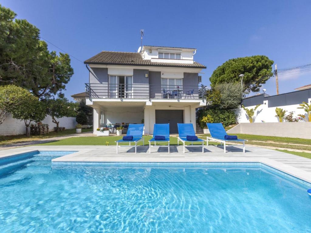 a house with a swimming pool and blue chairs at Villa Mi Capricho by Interhome in Calafell