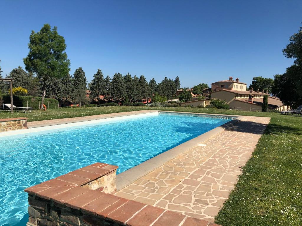 a swimming pool with a brick walkway next to a yard at Appartamento Pino in Trequanda