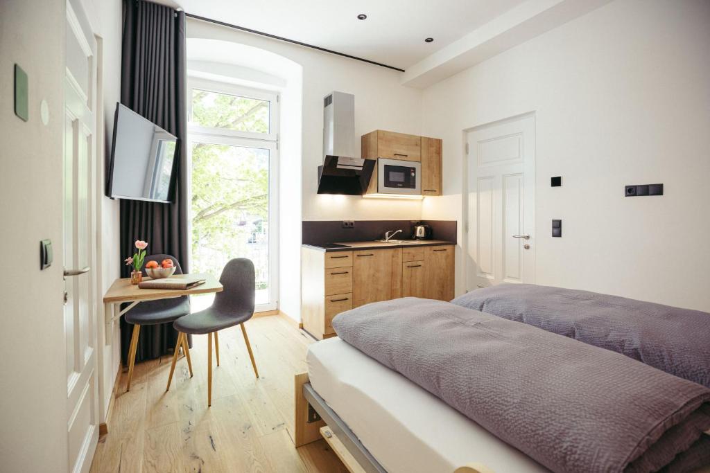 a bedroom with a bed and a desk and a kitchen at Freienfeldhof Gala in Lagundo
