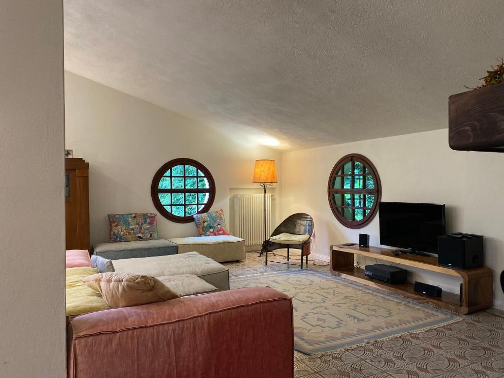 a living room with a couch and a tv and two windows at Villa Gioia sui colli Euganei in Torreglia