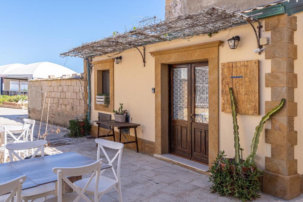 a house with a table and chairs and a wooden door at Casamari nel centro di Marzamemi in Marzamemi