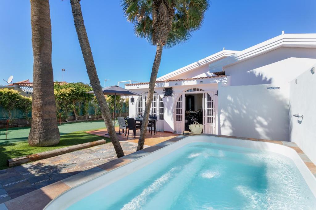 a swimming pool in front of a house with palm trees at Exclusive Villa with Heated Pool in Maspalomas