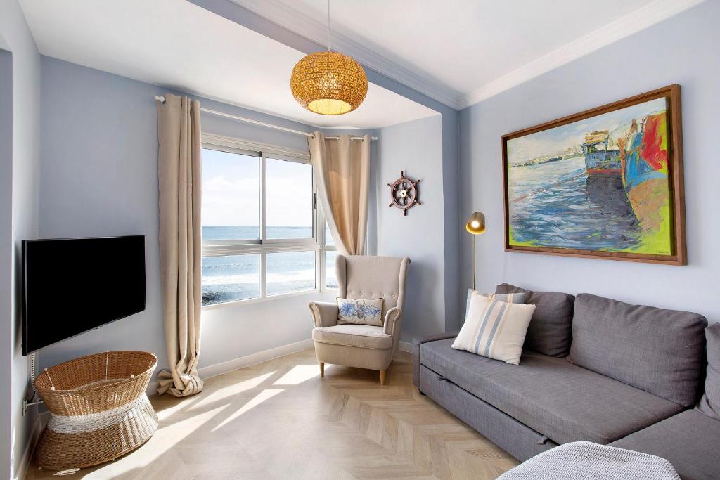 a living room with a couch and a tv at Ocean Side Arinaga in Arinaga