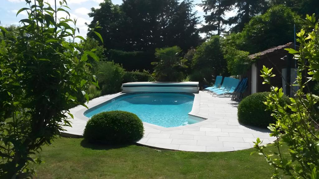 a swimming pool in a yard with blue chairs at La Grange De Vauviault in Bressuire