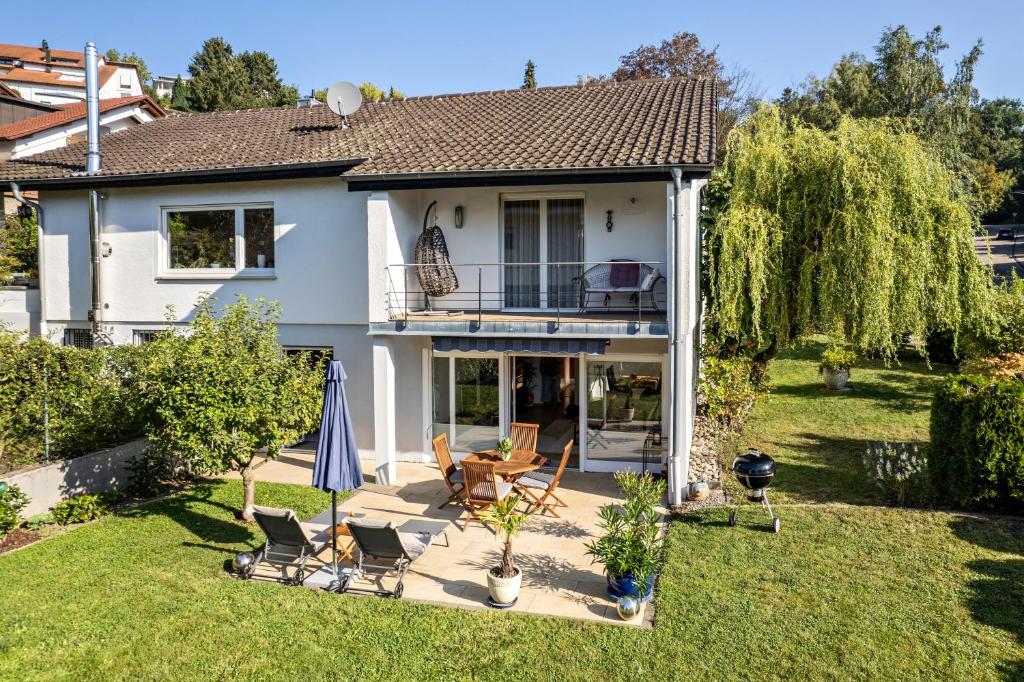 a house with chairs and an umbrella in the yard at Ferienwohnung Kuckucksnest in Lahr