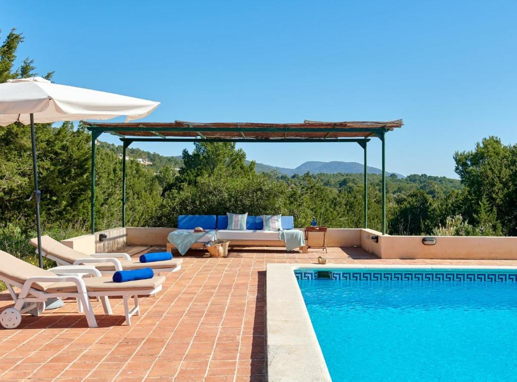 a swimming pool with chairs and an umbrella next to a swimming pool at Can Roca in Illes Balears