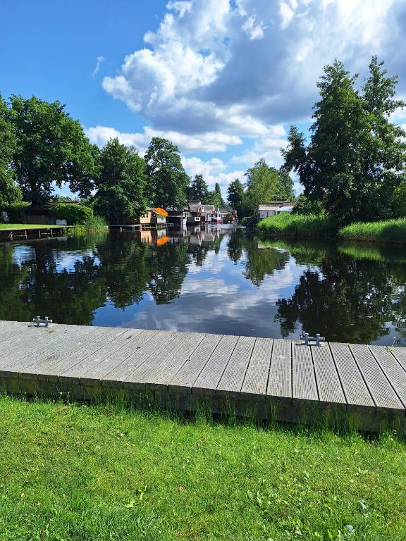 a body of water with a wooden walkway and houses at Ferienhaus am Wasser, Bootshaus in Güstrow