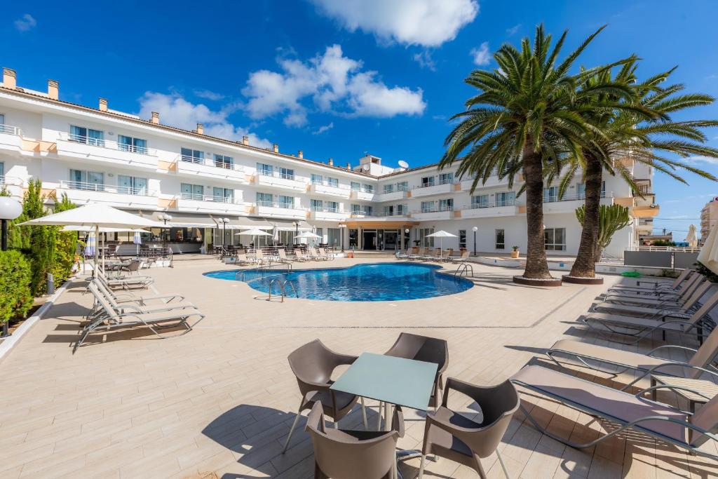 a hotel with a pool and chairs and palm trees at Apartamento Via Alemanya in Can Picafort