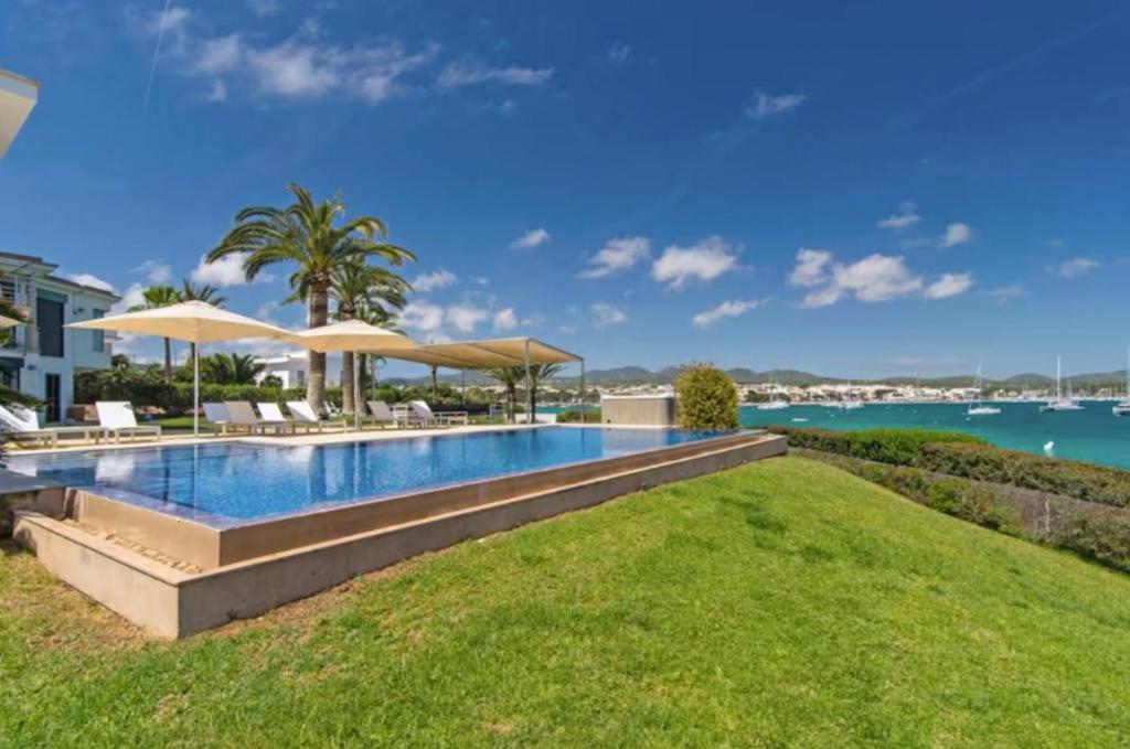 a swimming pool with umbrellas and the water at Sa Bateria in Portocolom