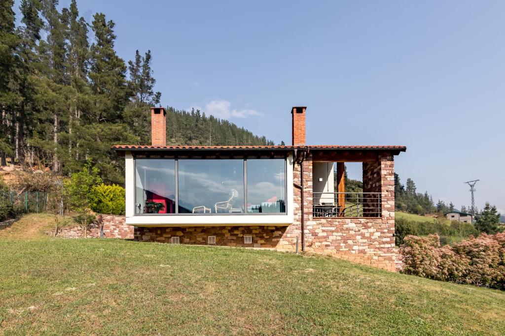 a brick house with a large window on a hill at La Riega Del Peral in Ojedo