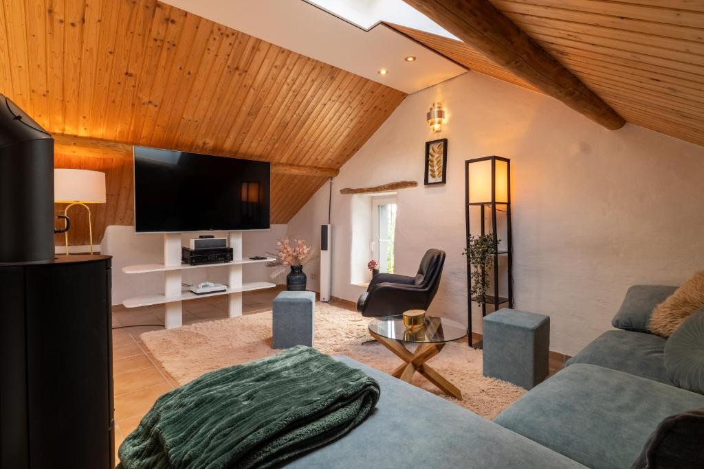 a living room with a couch and a tv at Kleines Eifel Backhaus mit Sauna in Feuerscheid