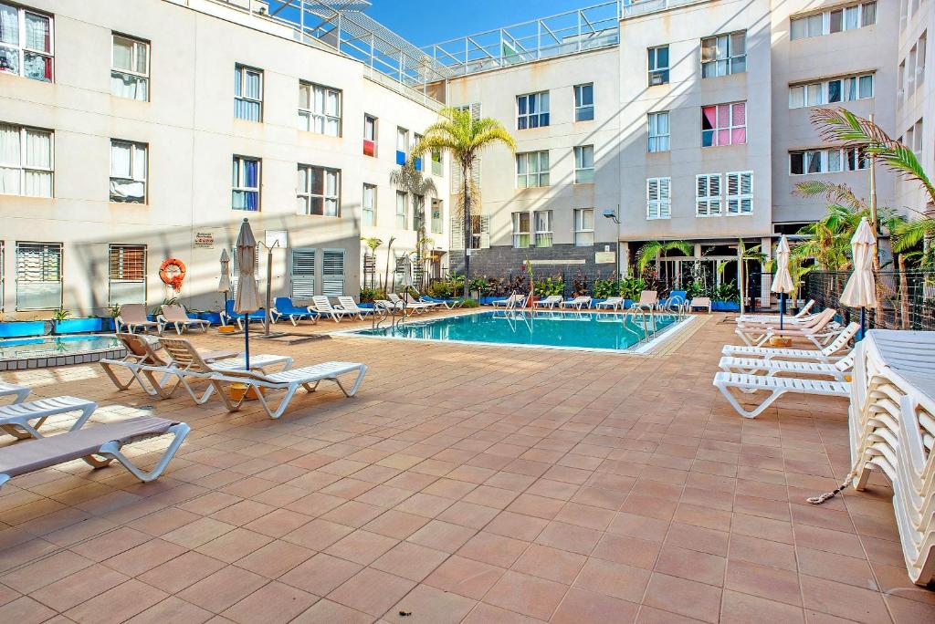 a swimming pool in a hotel with lounge chairs at Playa Sardina in Gáldar