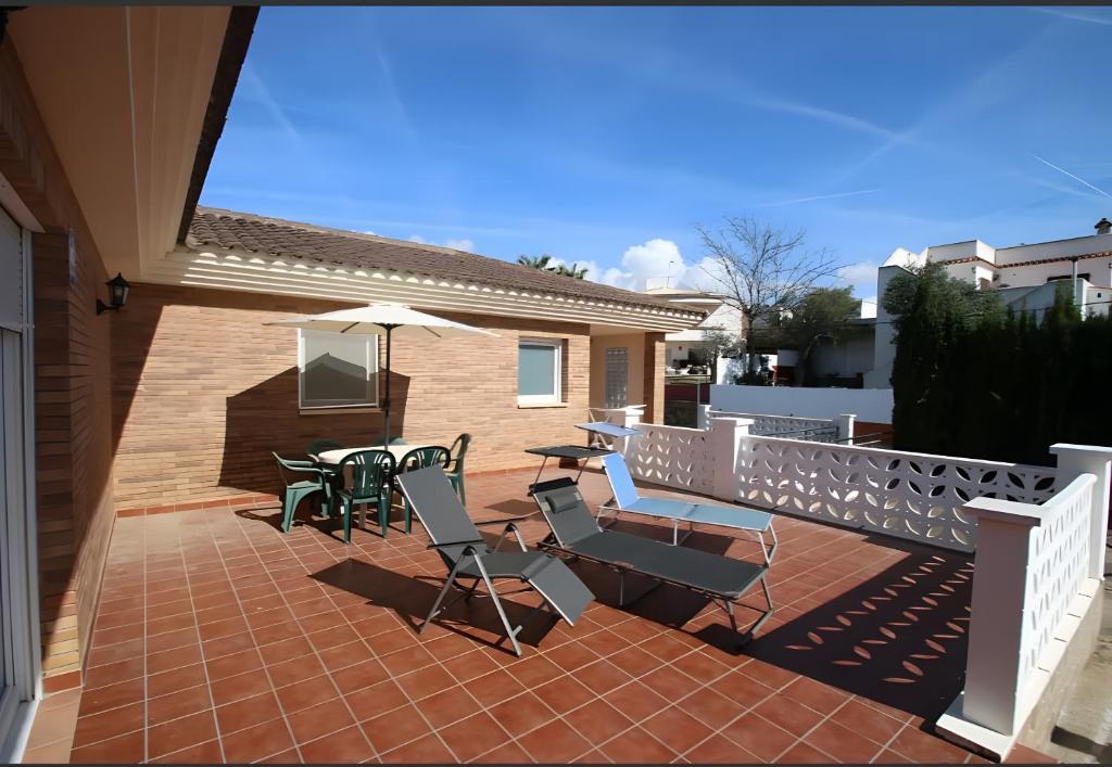 a patio with chairs and a table and an umbrella at Villa María Magdalena in Cambrils