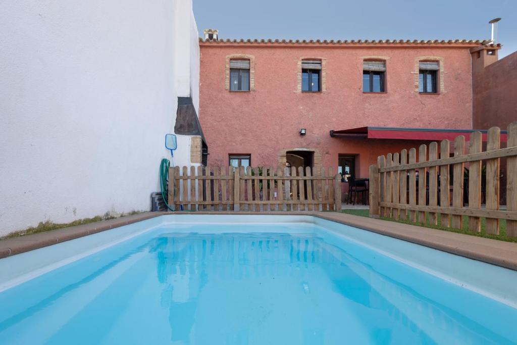 a swimming pool with a fence and a building at Les Orenetes casa rural in Sant Jaume dels Domenys