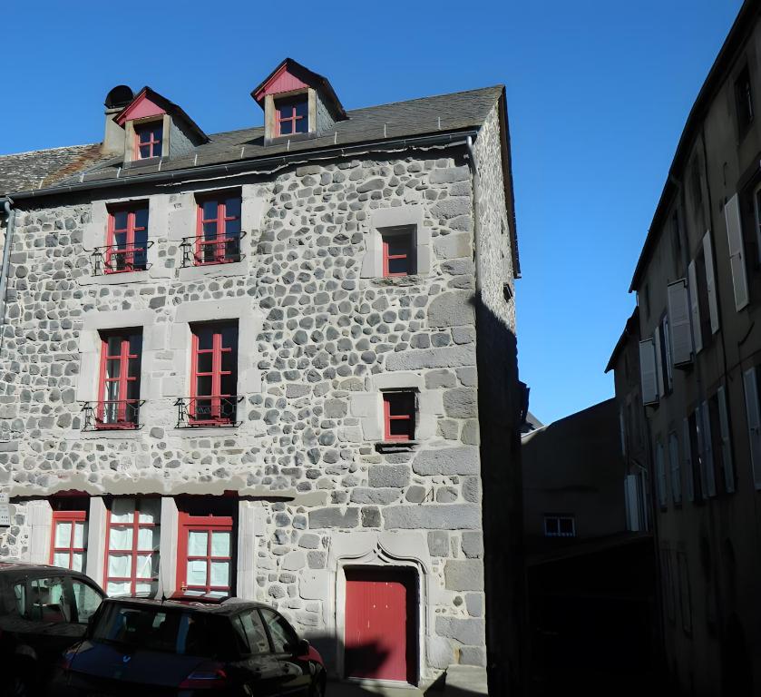 an old stone building with red windows on a street at La Maison De Marie in Murat