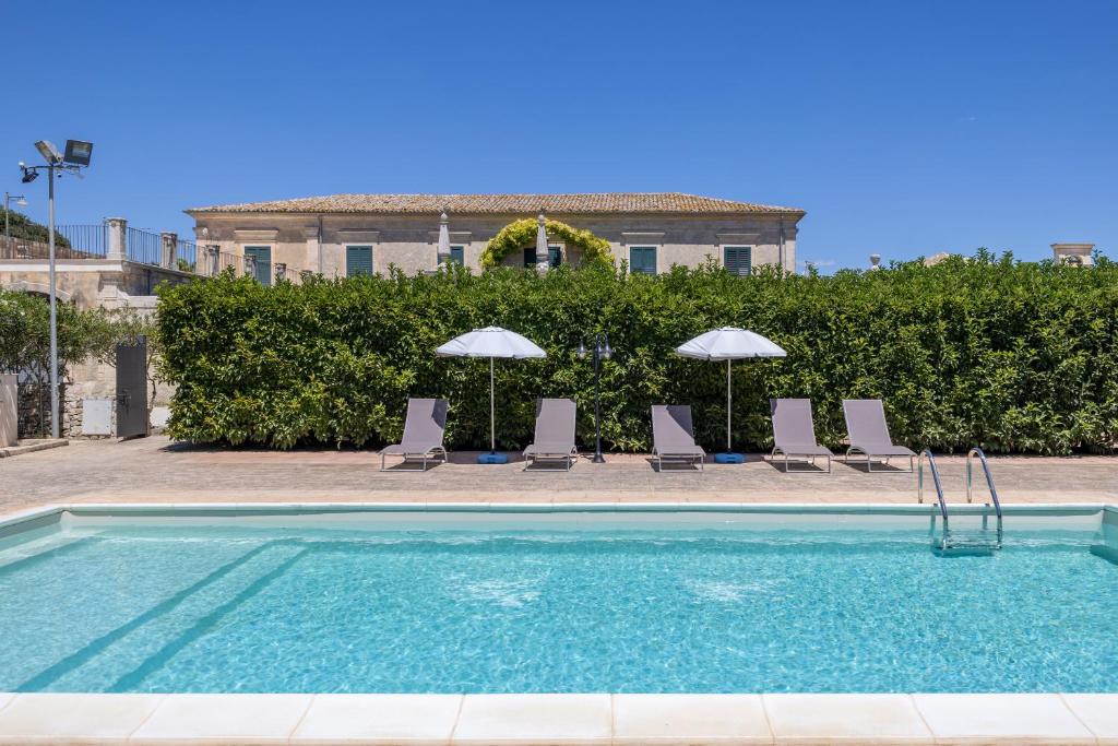 a swimming pool with chairs and umbrellas at Villa Aguglie Con Piscina in Modica