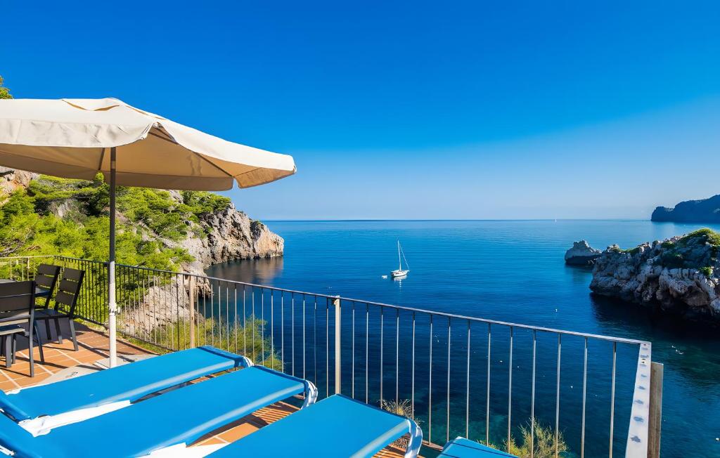 a balcony with chairs and an umbrella and the ocean at Cala Deia in Deia