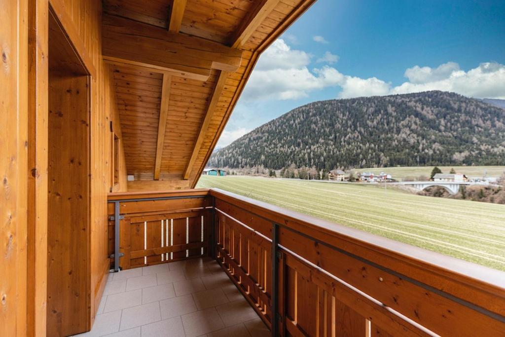 a balcony with a view of a field and mountains at Unterhauserhof App C in Valdaora