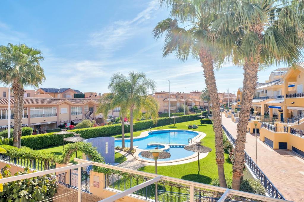 a view of a courtyard with palm trees and a swimming pool at Casa en playa con piscina Novamar in Santa Pola