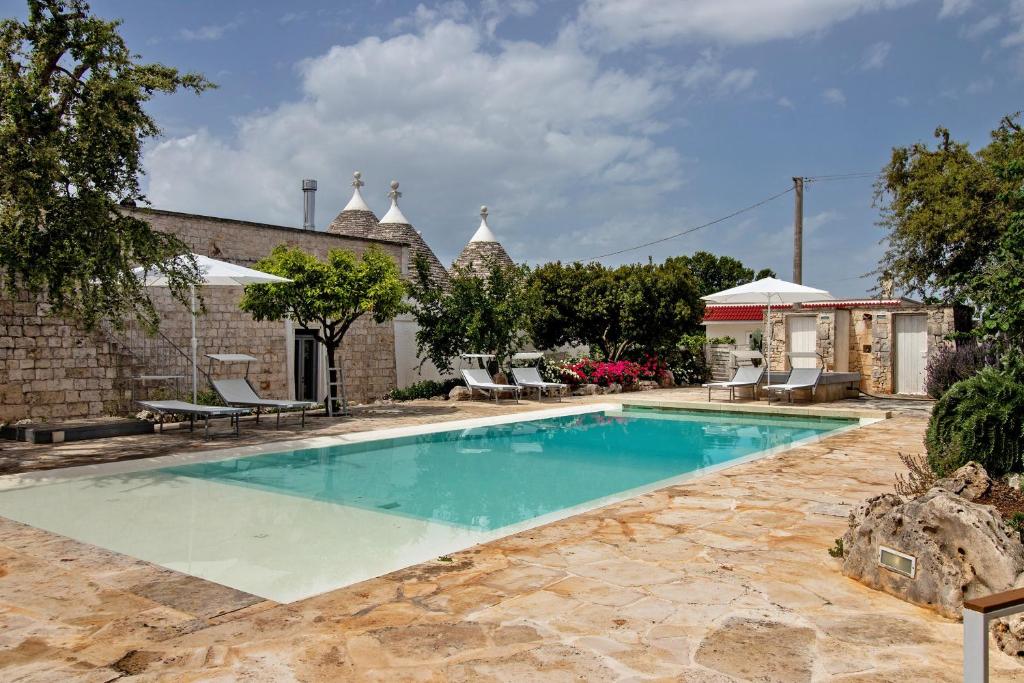a swimming pool in a yard with chairs and a building at La Dimora dello Zio, with pool in Ostuni