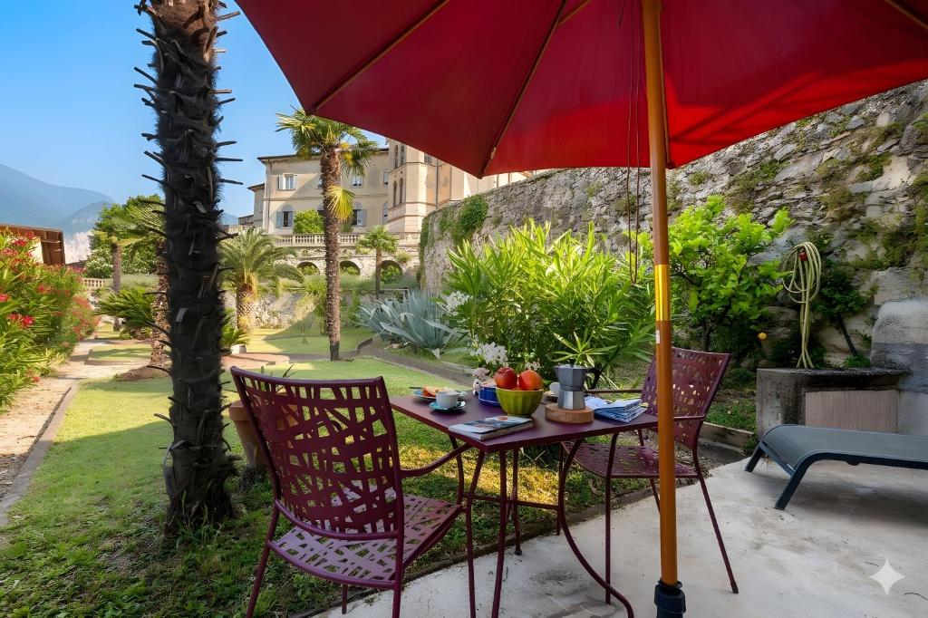 a table and chairs under a red umbrella at La Guardiola I By Immobilux in Riva del Garda