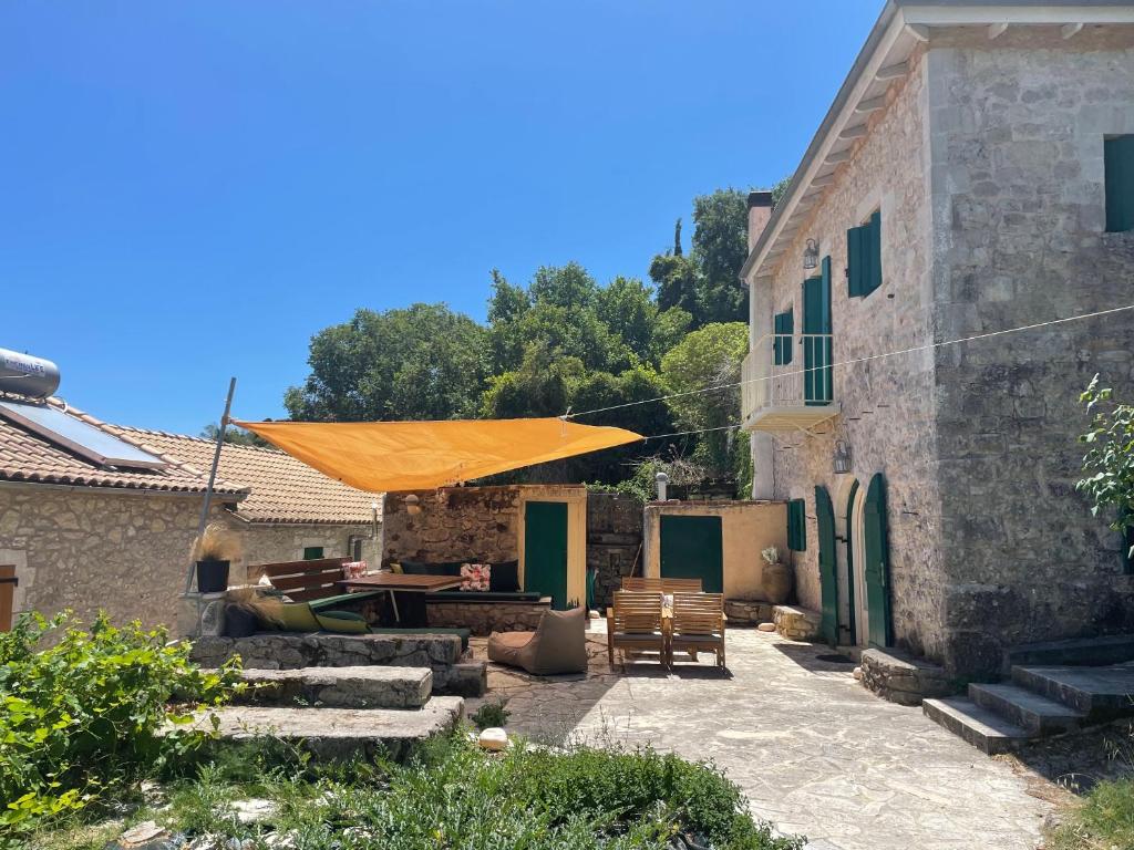 a patio with an orange umbrella and a building at Traditional Stone House in Lazaráta