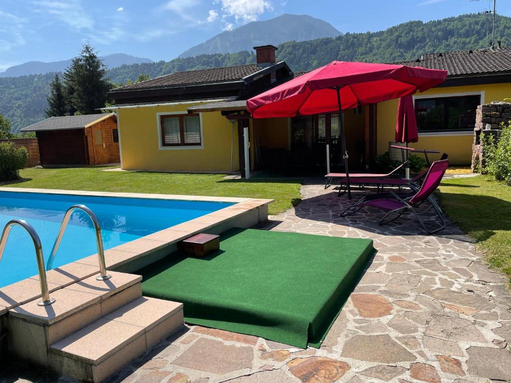 a pool with a red umbrella and a table and a green mat at Haus Linsendorf in Gallizien