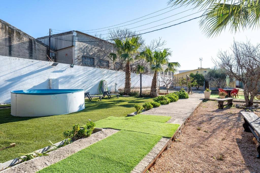 a garden with grass and benches and palm trees at Masía Costa Daurada in Tarragona