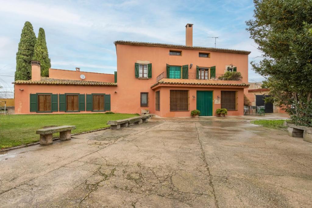a large orange house with benches in front of it at Ca l'Andorrà in Vila-Sana
