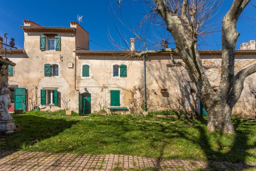 an old house with green shutters and a tree at Véritable Mas Provençal À La Palud in La Palud-sur-Verdon