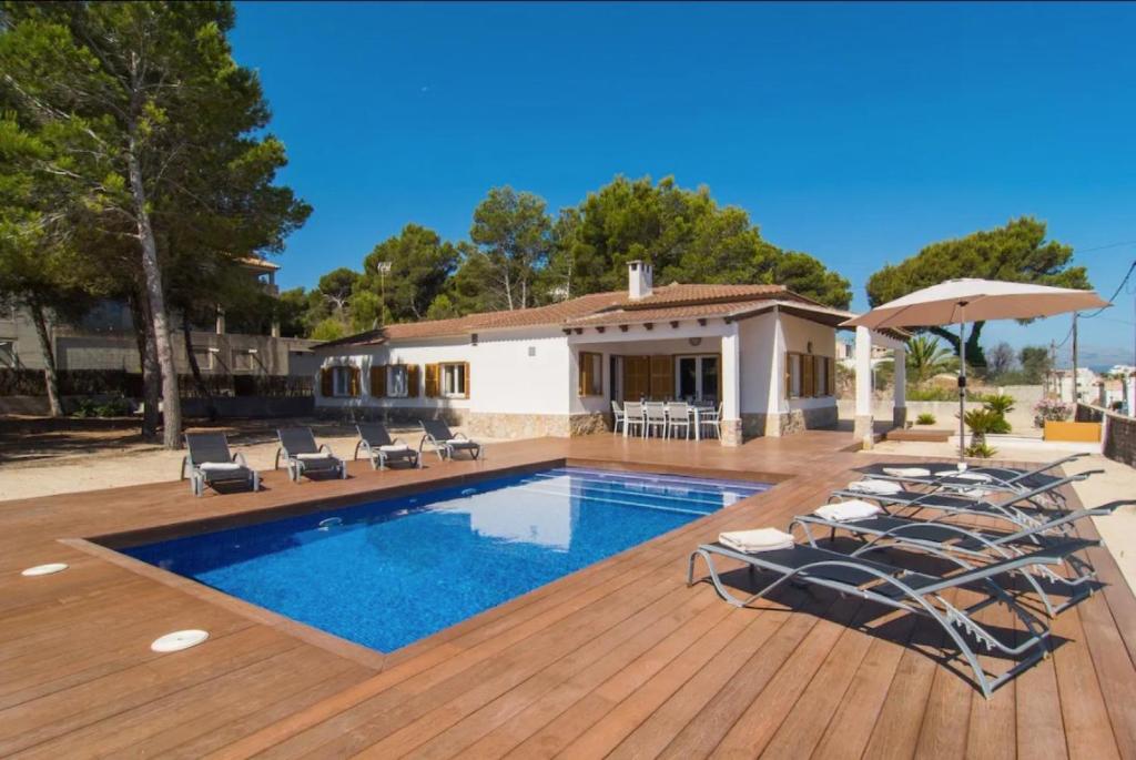 a swimming pool with chairs and a house at Anglesos in Can Picafort