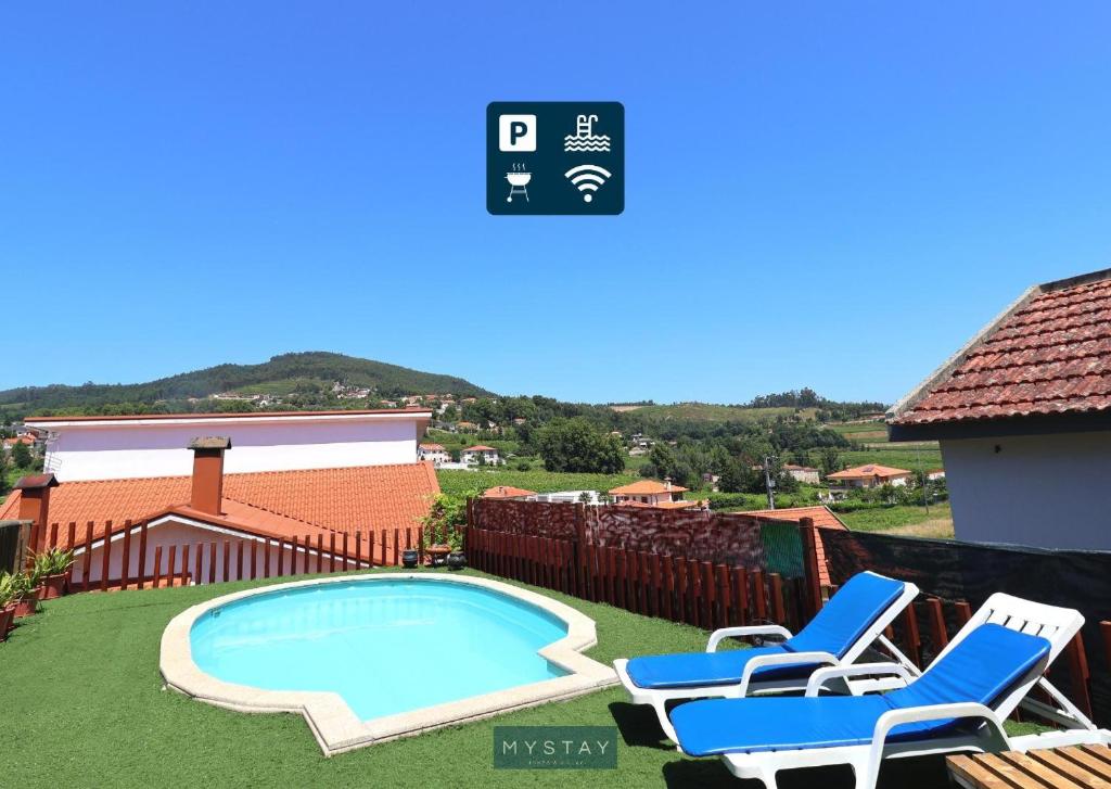 a swimming pool in a yard with chairs and a house at Casa Alto Das Fragas in Canedo de Basto