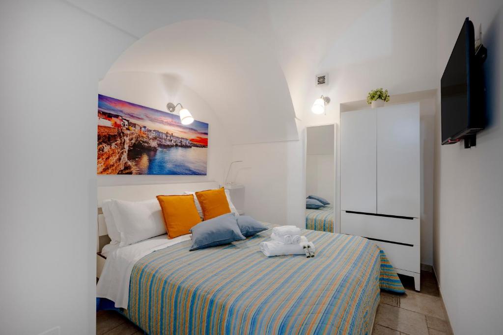 a bedroom with a bed with orange and blue pillows at Tritone 30 in Polignano a Mare