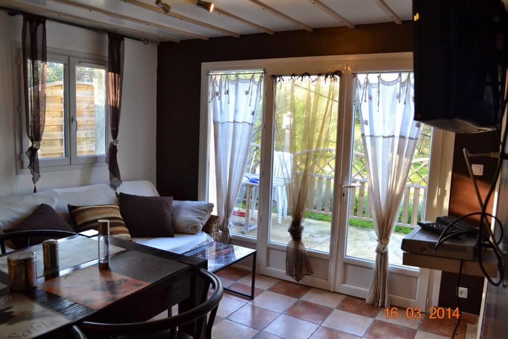 a living room with windows and a couch and a table at Rez-de-villa Taglio-Isolaccio in Taglio-Isolaccio