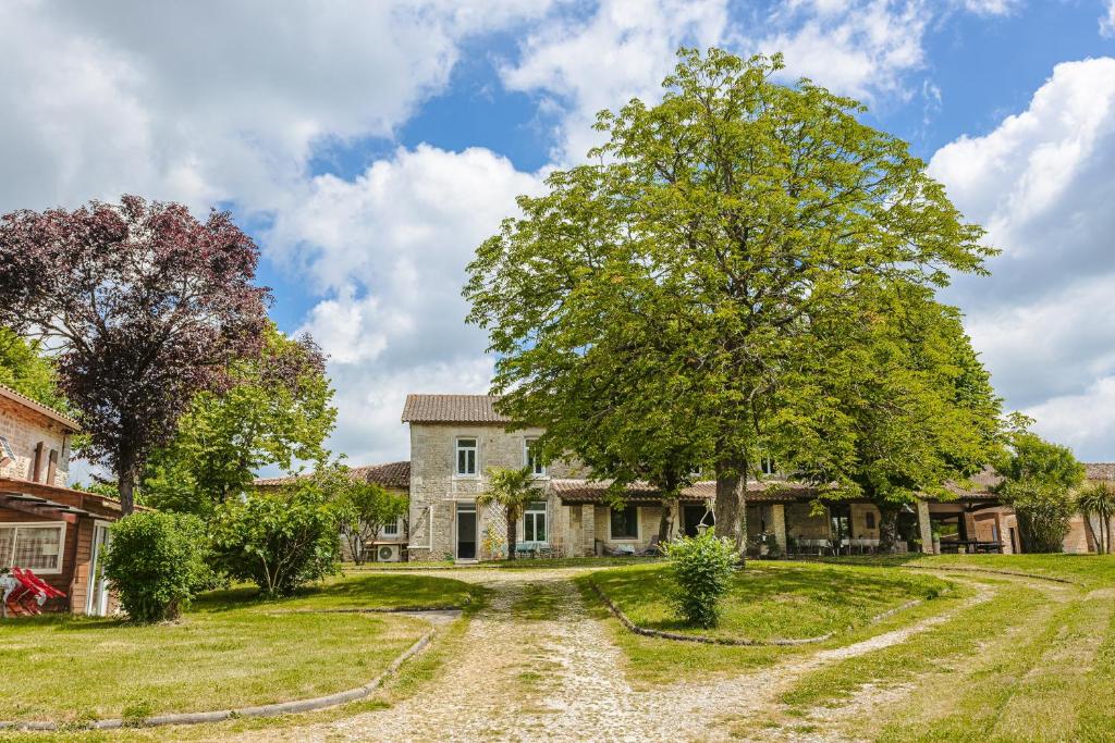 an old farmhouse with a tree and a dirt road at Chambre d'hote Emeraude in Genouillé
