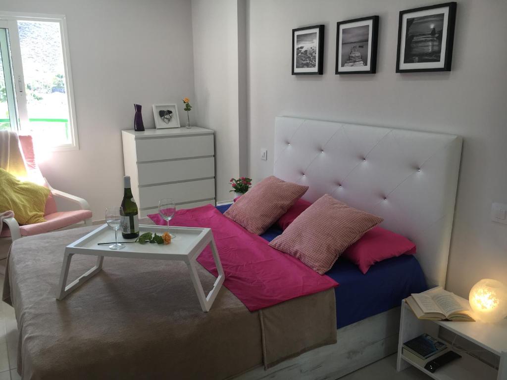 Una cama con almohadas rosas y una mesa en una habitación en Apartment Los Cristianos, en Los Cristianos