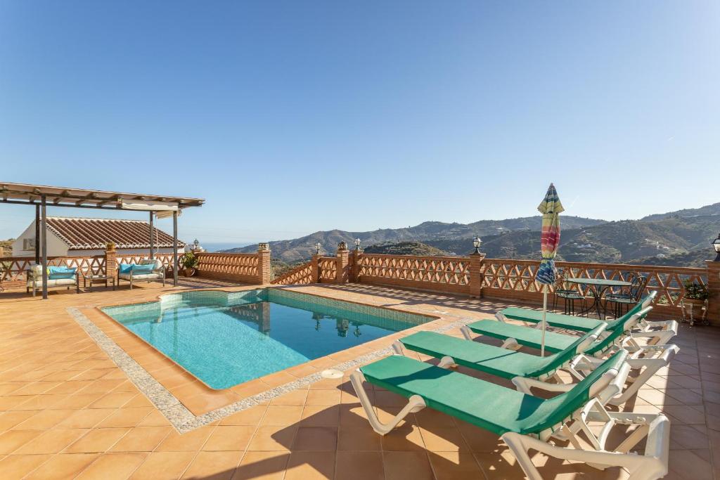 a swimming pool with chaise lounge chairs and a swimming poolvisor at Fuente luz cottage in Frigiliana
