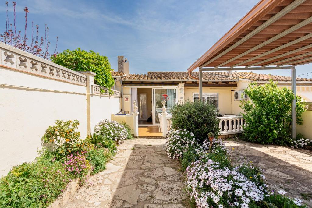 a house with a porch and flowers in front of it at Maison La Coquette L' Escala in L'Escala