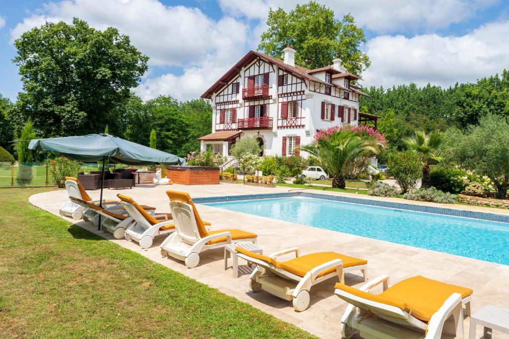 a pool with lounge chairs and a house at Villa d’Exception, Piscine, Parc in Soustons