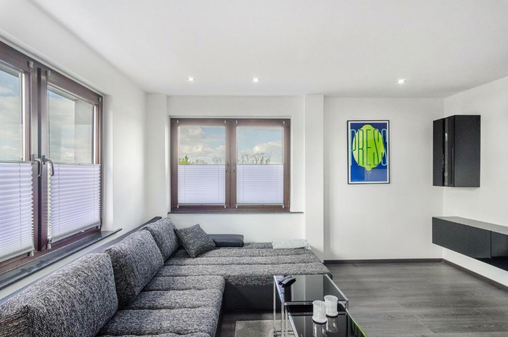 a living room with a large couch and windows at Moin, die Ferienwohnung in Wilhelmshaven