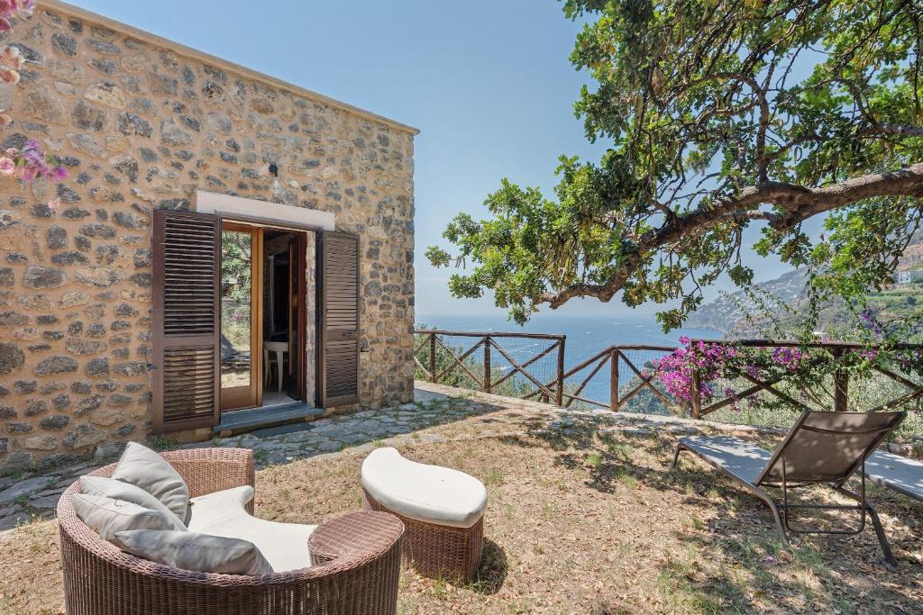 a patio with chairs and a table and a building at Romantico casale di lusso con Spa in Conca dei Marini