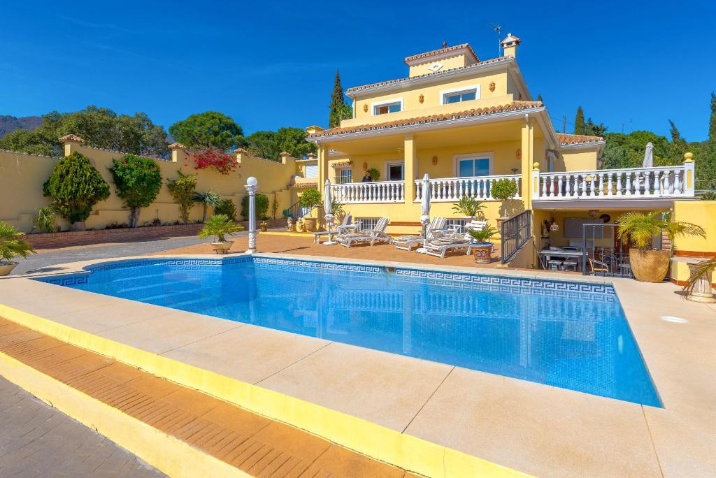 a villa with a swimming pool in front of a house at Villa Roca Penthouse in Estepona