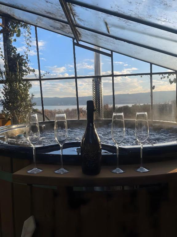 a bottle of wine and three wine glasses on a bath tub at Seeluft direkt am Wasser in Reichenau