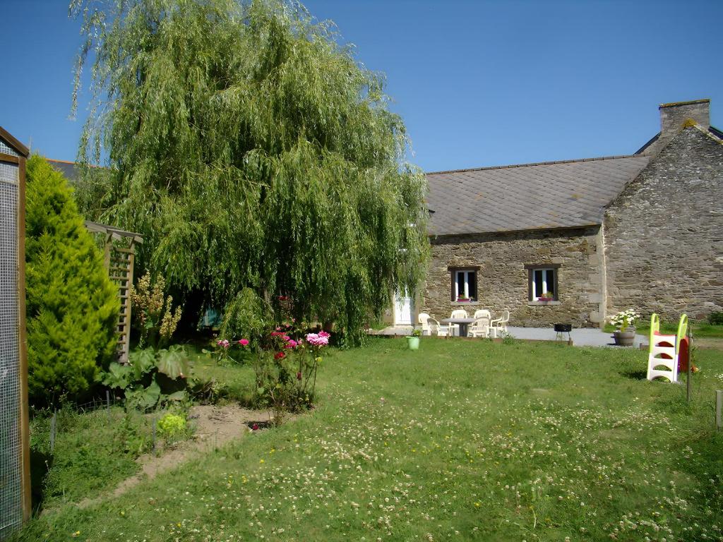 a house with a yard with a large tree at Gîte Joly in Corseul
