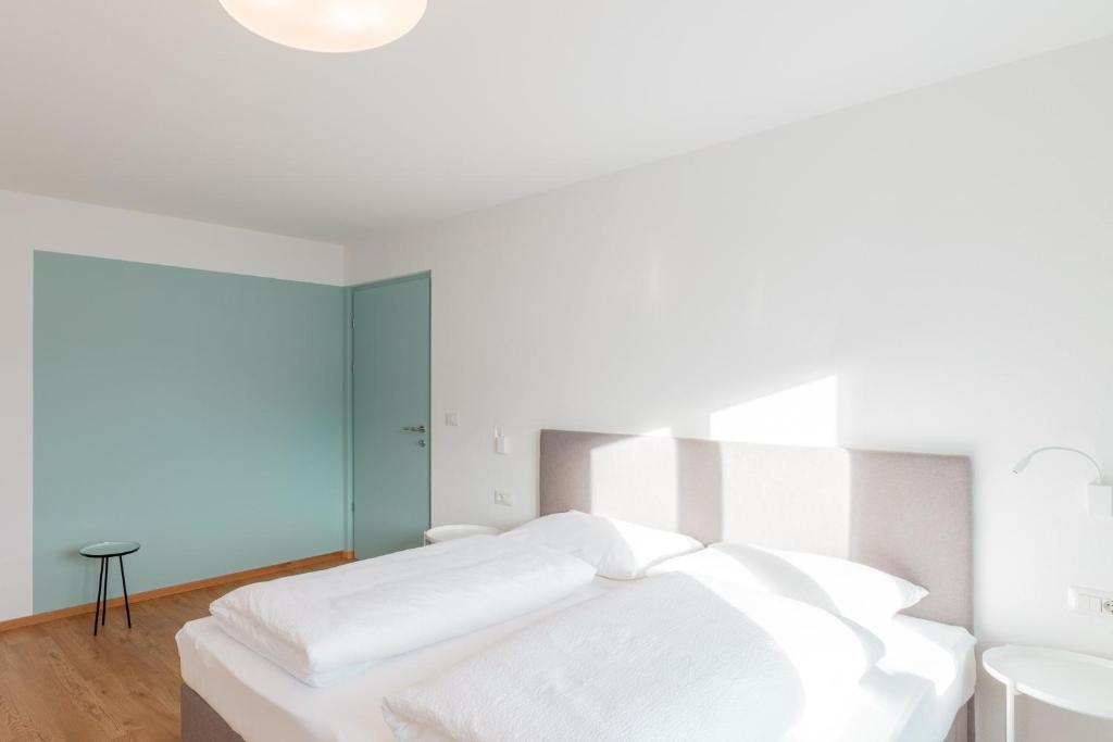 a bedroom with a white bed and a table at Hus Appartement - Nr. 4 in Valdaora