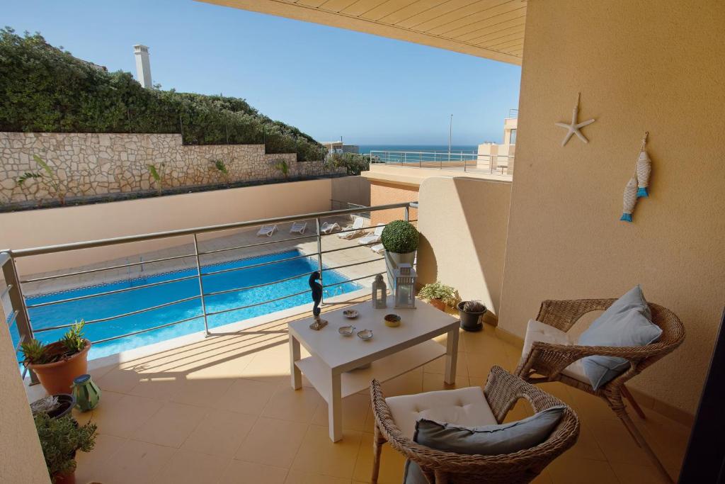 a balcony with a table and a view of the ocean at Praia Areia Branca in Lourinhã