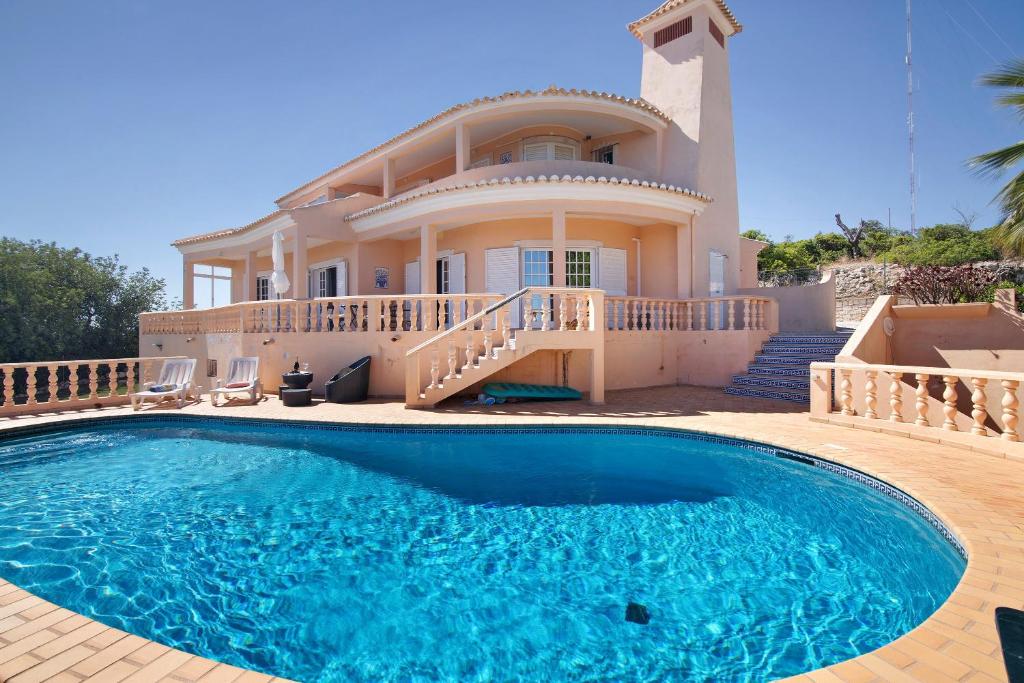 a villa with a swimming pool in front of a house at Quinta da Violeta in Loulé