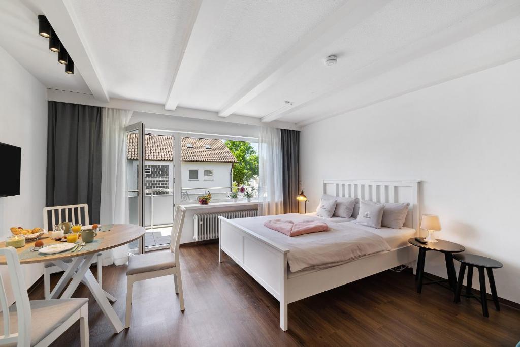 a bedroom with a white bed and a dining room at Andrea in Langenargen