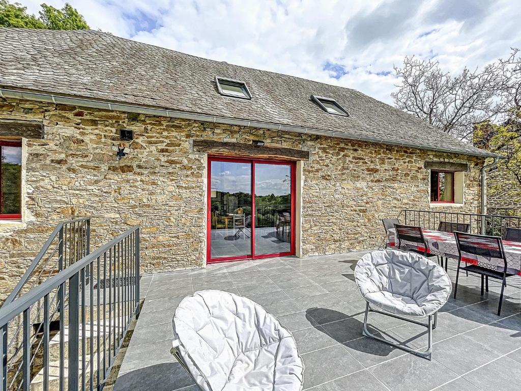 a patio with chairs and a stone building at Maison authentique et au calme in Beynat
