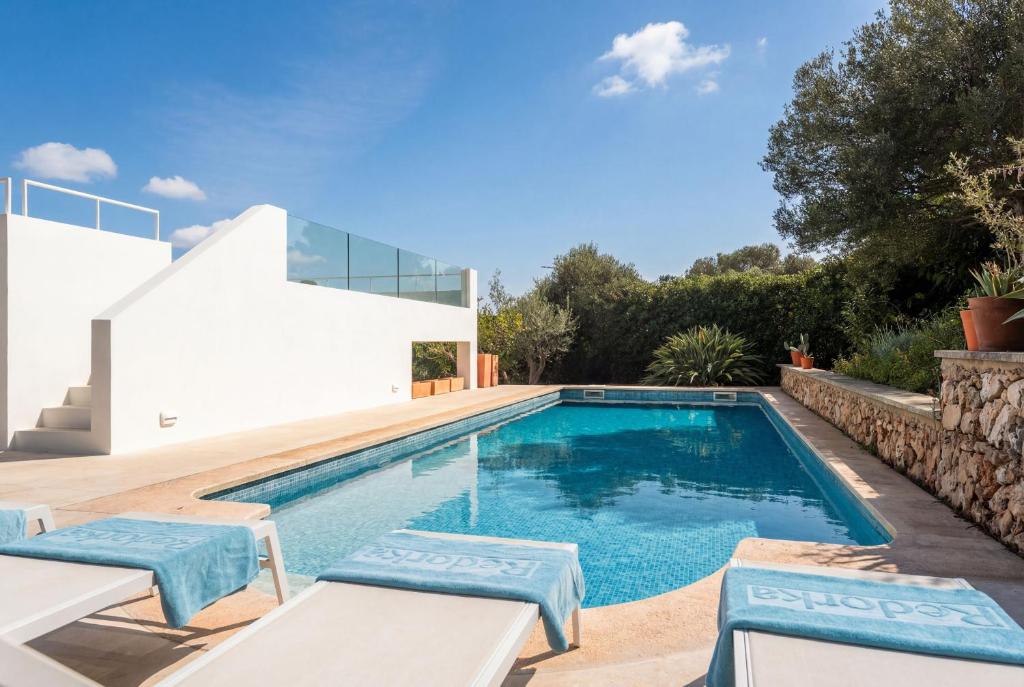 a swimming pool with two chairs and a house at Horizonte Sur in Binibeca
